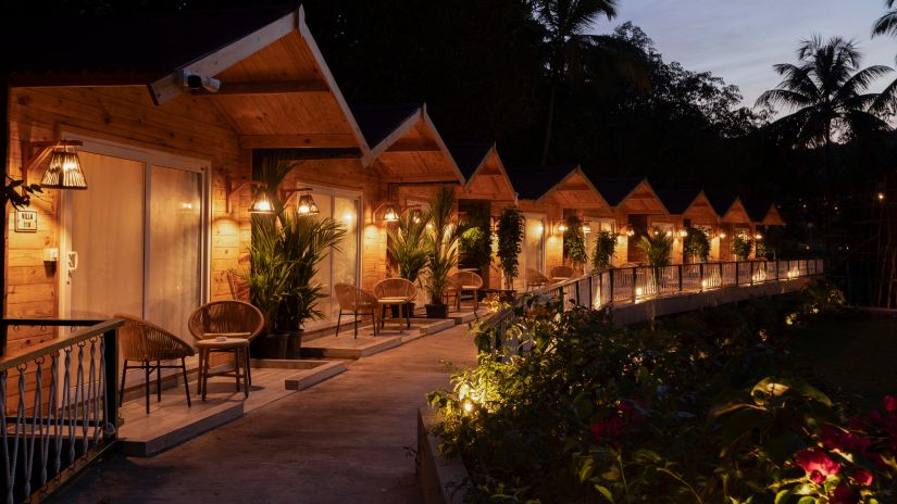 Row of cottages in full view in the night with trees in the background - Stone Wood Jungle Resort, Dandeli