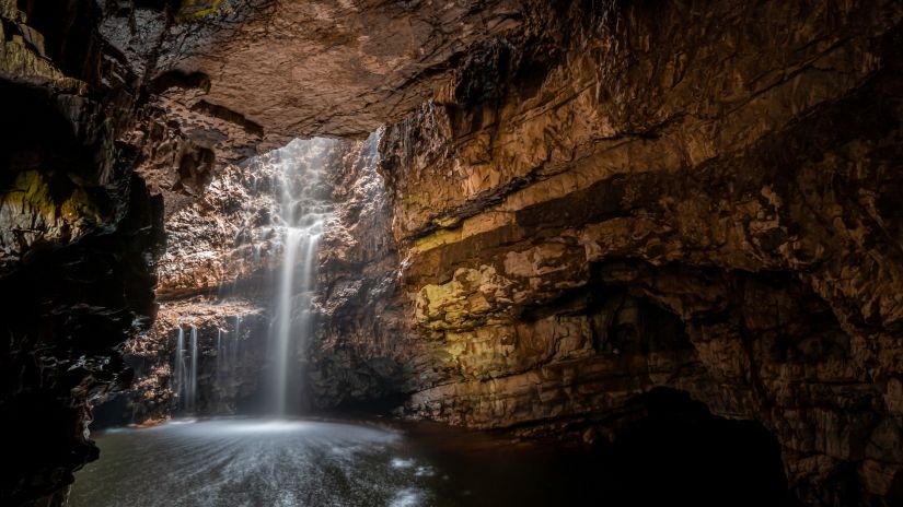 water entering a cave by means of a waterfall