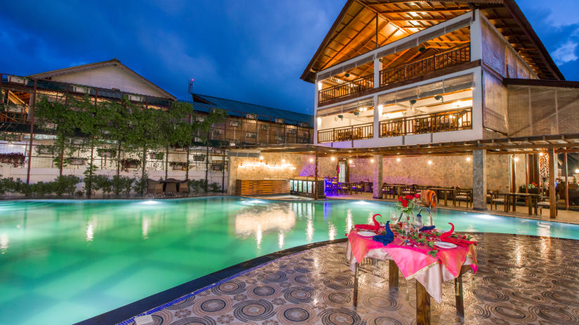 a table next to a swimming pool decorated with pink sheets and drinks on it captured after sunset - Symphony Summer Sand Beach Resort And Spa, Neil Island