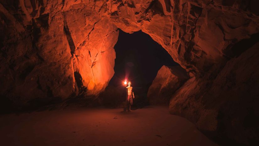 a person holding a flashlight inside a cave