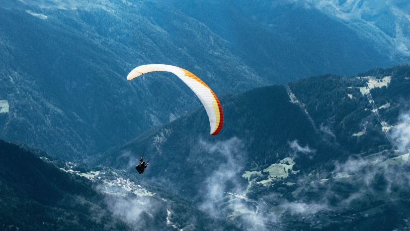 A person paragliding in the mountains on a cloudy day