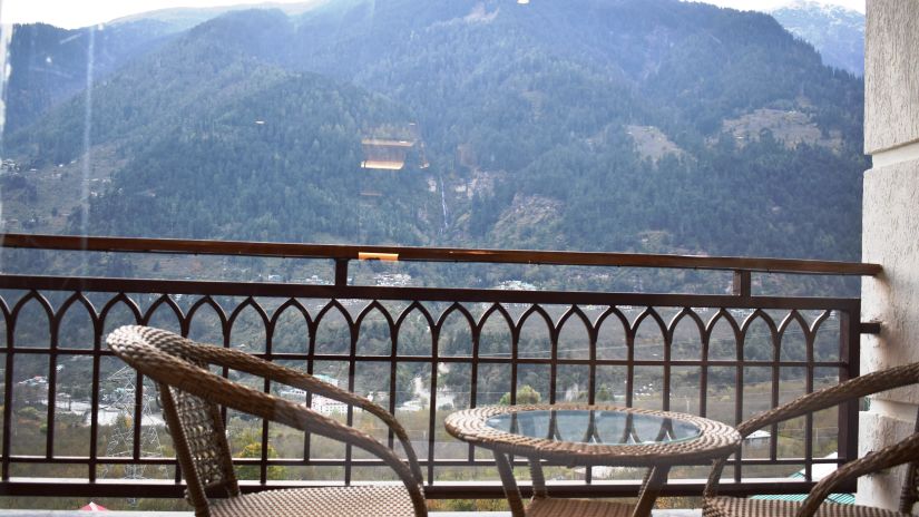 Two chairs and a table on a balcony with a view of the mountains