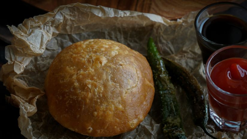 A plate of Kachori kept on a paper with a chilly and tomato sauce and mint chutney next to it