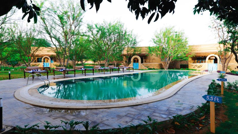 Swimming pool surrounded by trees at Themis Mudhouse - A Nature's Retreat Resort & Wellness