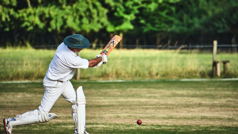 a batsman dressed in all white playing a cover drive 