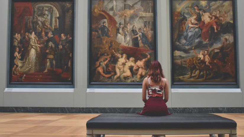 a person sitting in a gallery looking at paintings