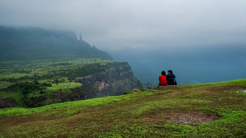 a couple seated at th edge of a cliff with a foggy backdrop