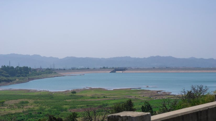 An overview of a dam from afar with hills in the background