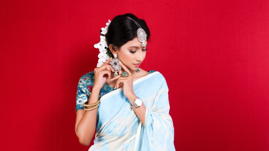 a bride posing for a picture with a red background while decked up in a kachipuram saree