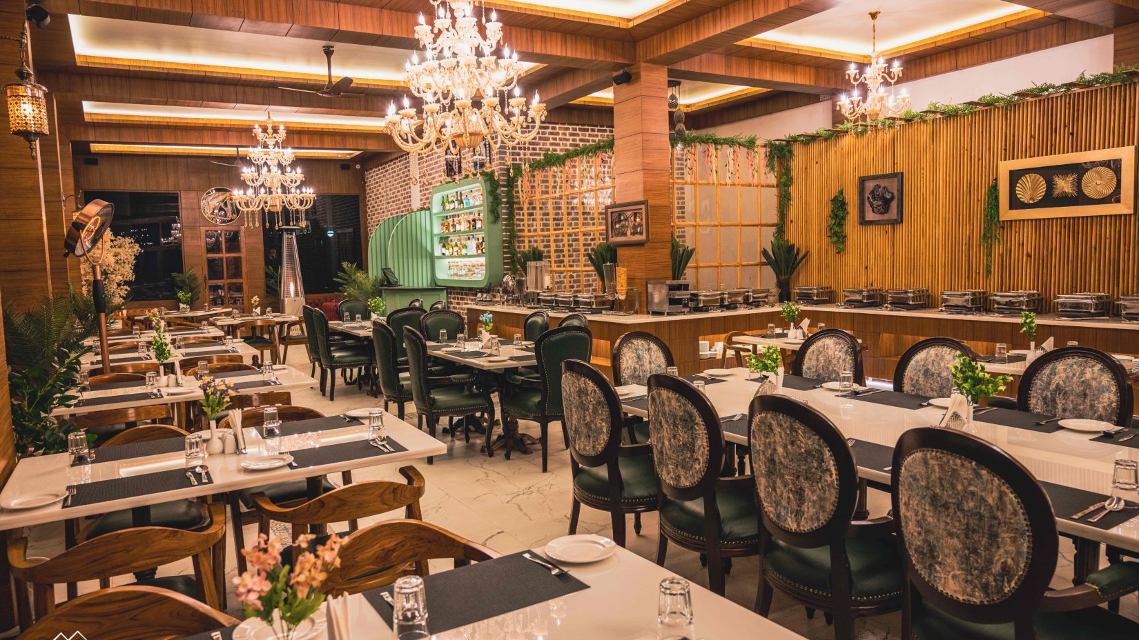 interior of Alpenrose Restaurant arrayed with dining tables and chairs with chandelier hanging from the ceiling at The Tattva Boutique Resort, Joshimath