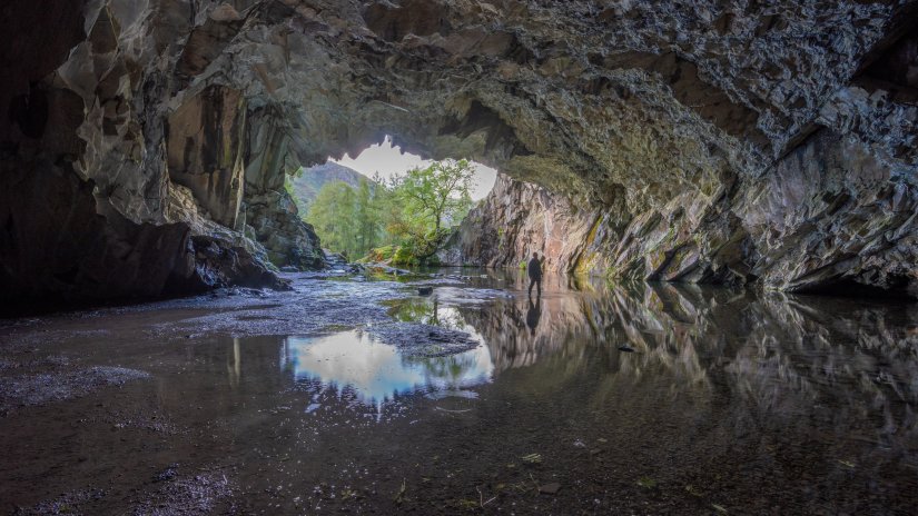 a person checking out a cave with the entrance in the background