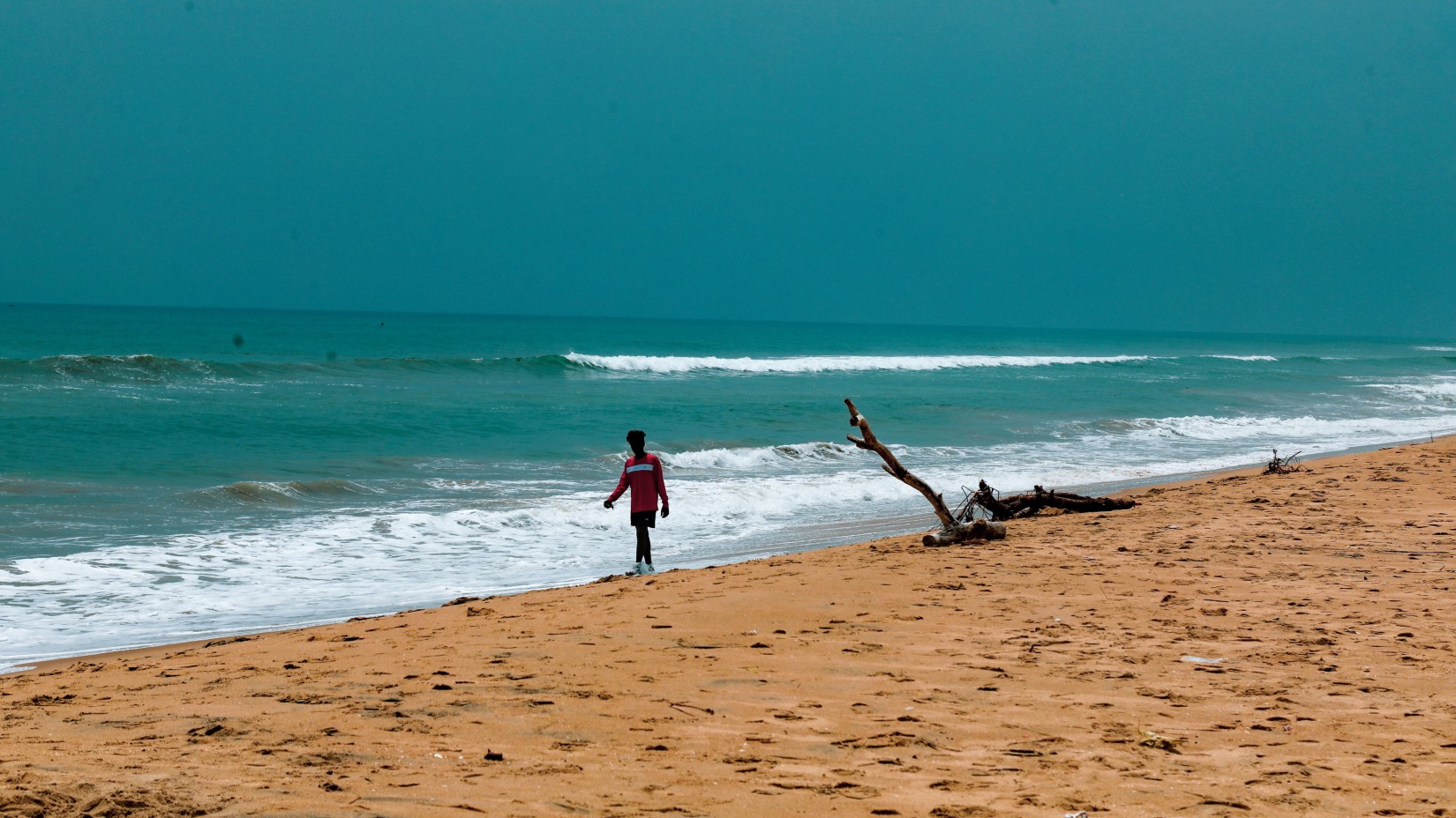 a Person walking on a beach with waves overlapping on the shore