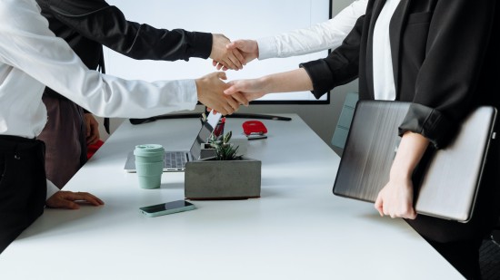 Four people shaking hands at the boardroom