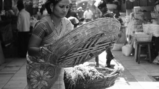 a black and white image of a woman holding a bamboo basket