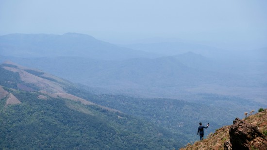 A person standing on top of Mulayanagiri hills while looking at the valley below