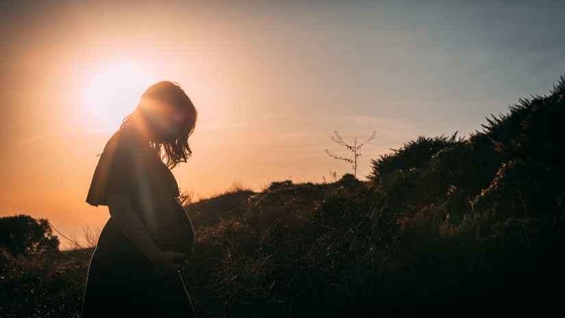 a pregnant woman standing during sunset
