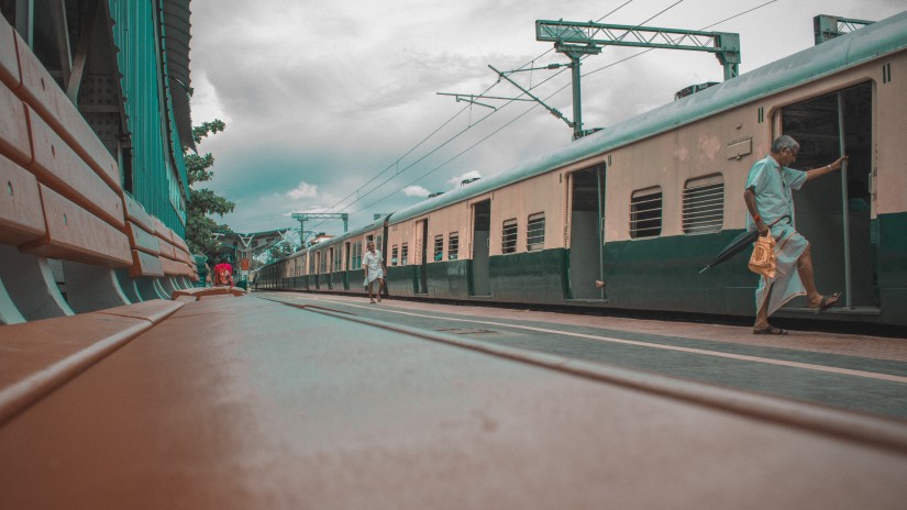 a Person boarding a train in a railway station with clouds in the background