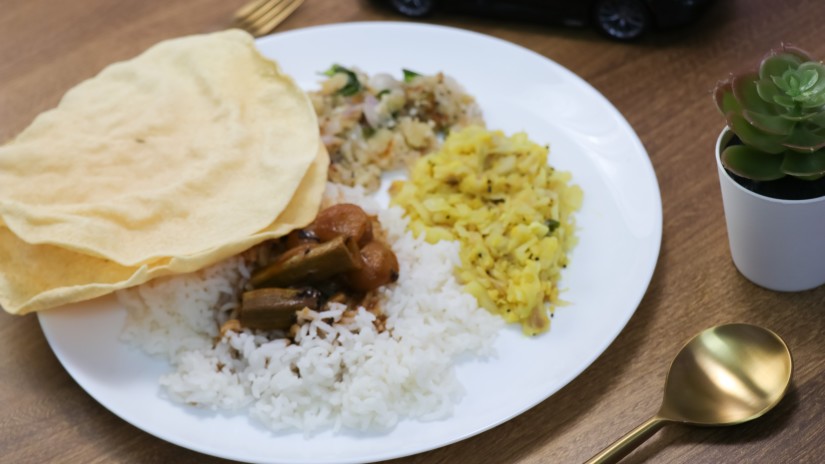 A plate of south indian food with sides and papad kept on the table