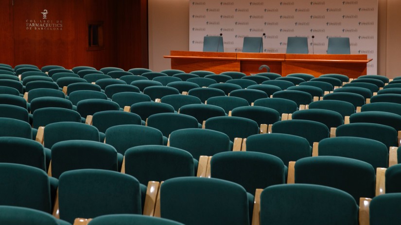 a hall arrayed with green chairs and an orange podium placed in front of it