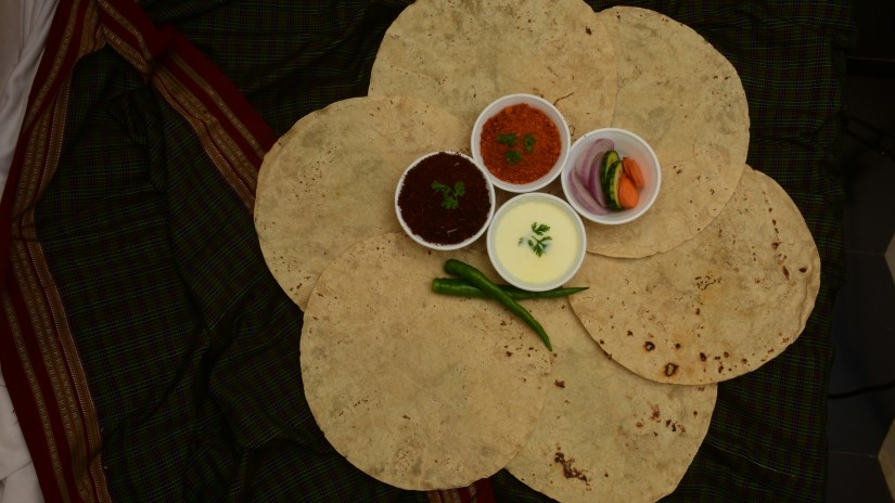 an aerial view of many rotis kept in a circular shape with dips and chutneys kept on it