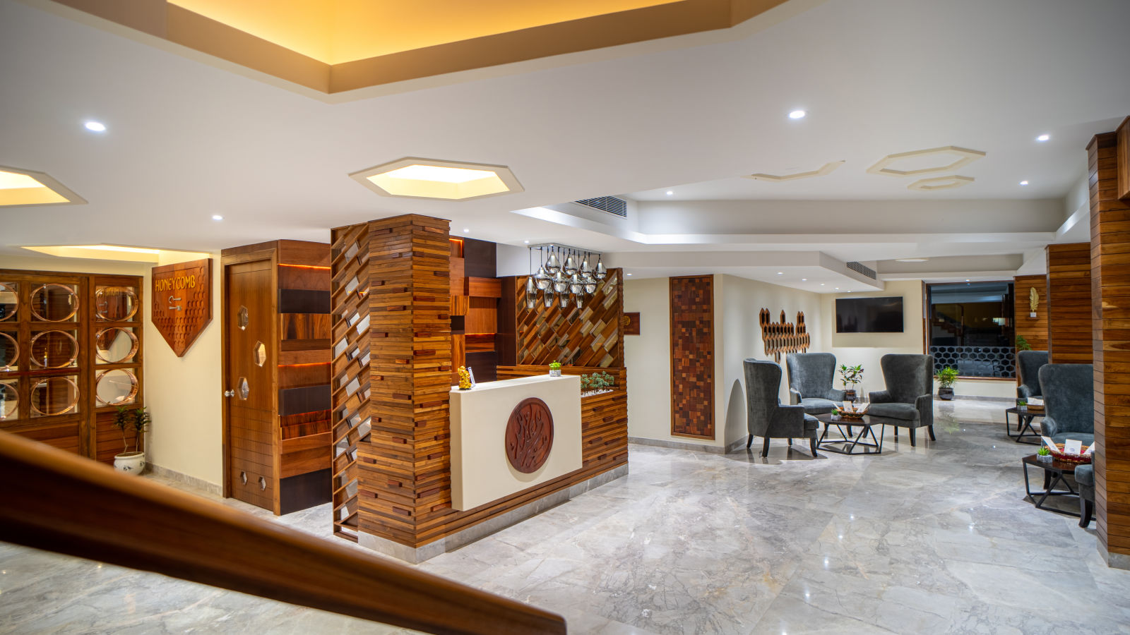 A spacious hotel lobby with modern wooden decor, stylish seating and ambient lighting - Coral Reef Hotel & Spa, Port Blair