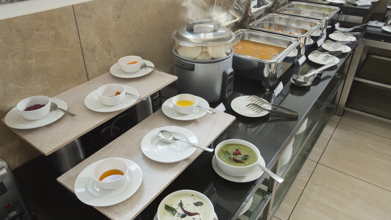 A buffet table with a selection of soups and hot dishes in a hotel dining area - De Venetian by TGI, Brookefield