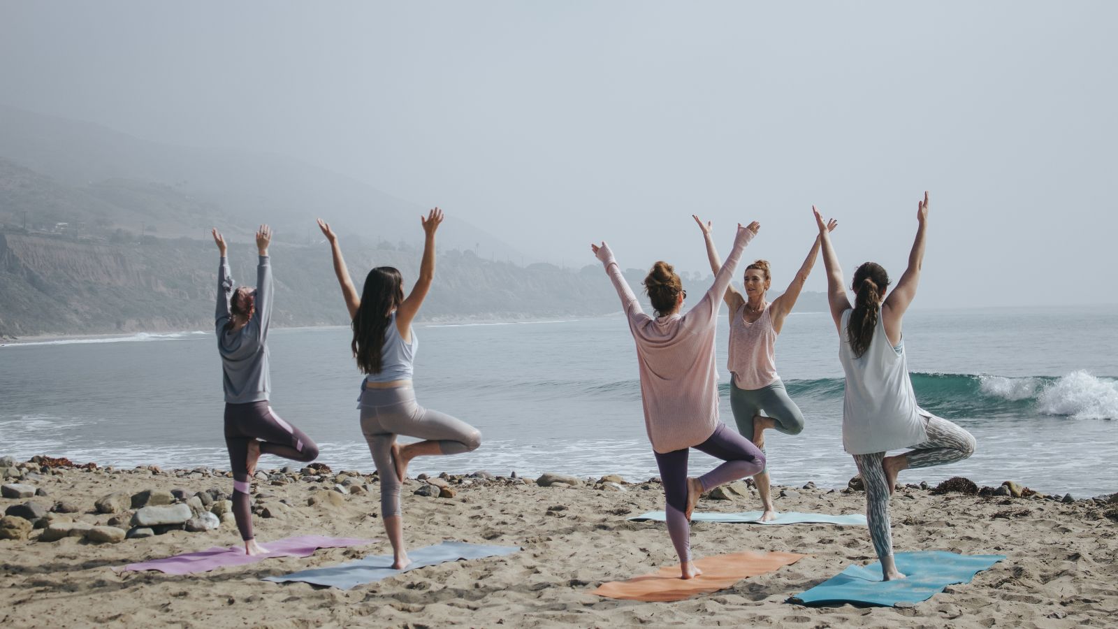 People practicing yoga on the beach - Monsoon and ayurveda - gamyam Retreat