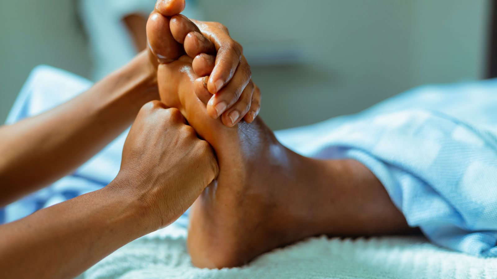 a person massaging the foot of a customer with both hands