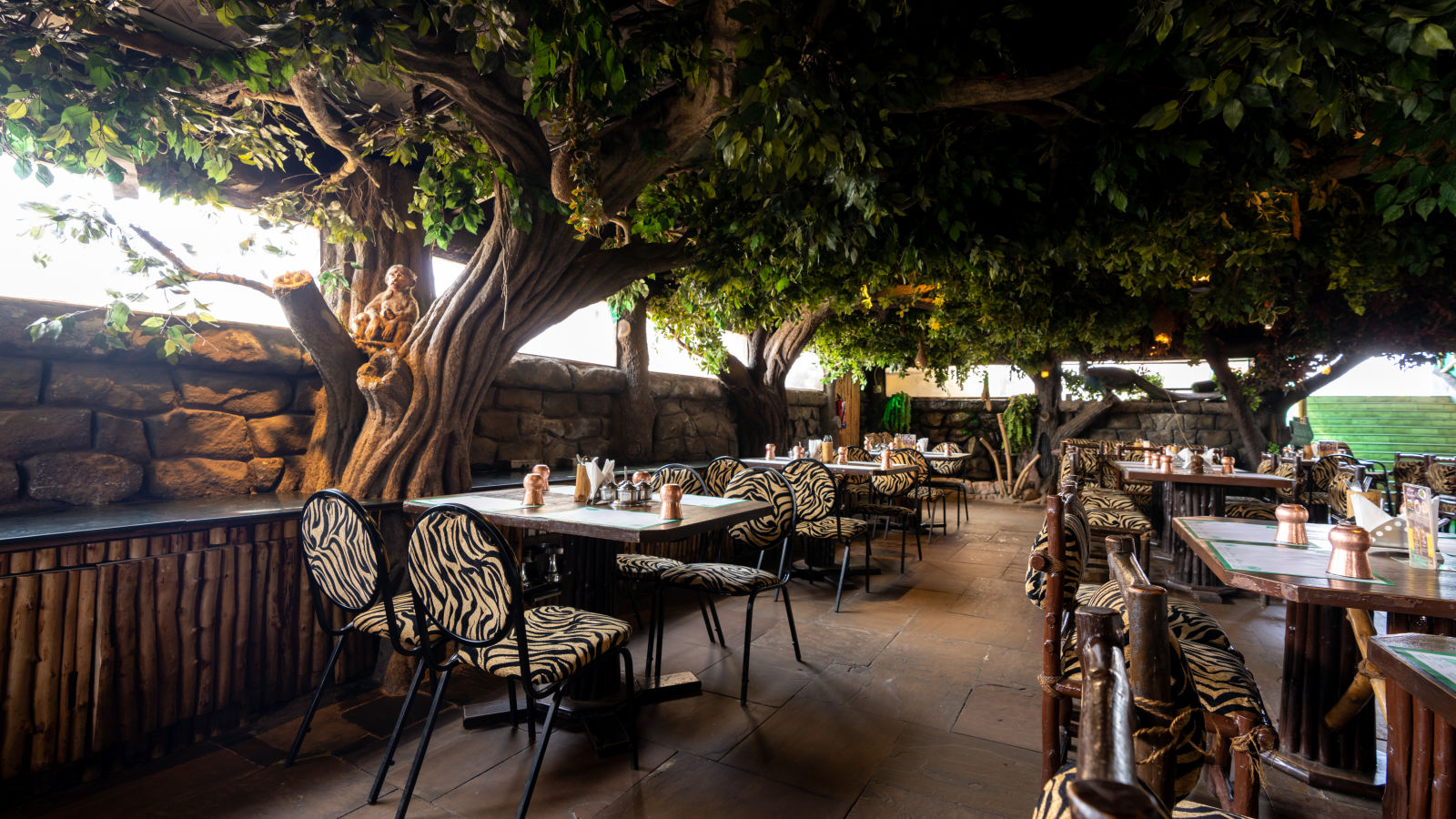 Seating arrangements inside a restaurant with trees on the side at Hotel Pai Vista, Mysore