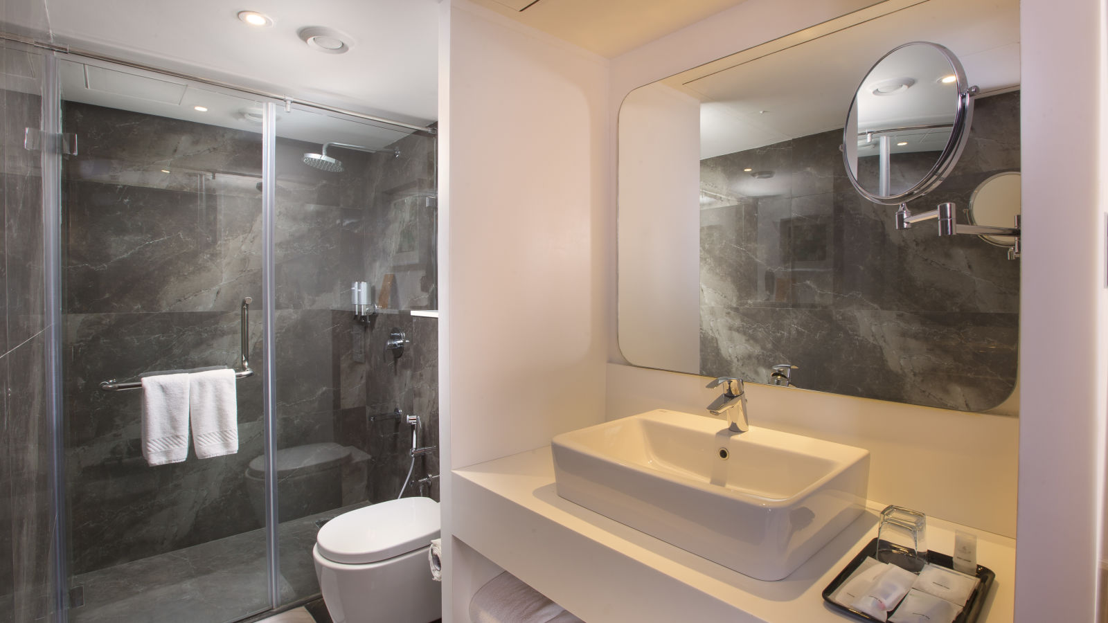 A view of a bathroom, highlighting the mirror and washbasin with toiletries provided - Hotel Southend by TGI - Bommasandra, Bangalore