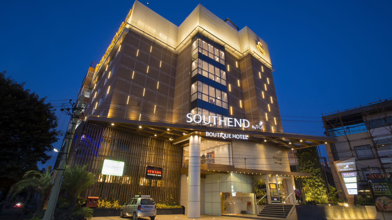 Another view of the illuminated facade of the Southend Hotel, with a dark blue sky in the background - Hotel Southend by TGI - Bommasandra, Bangalore