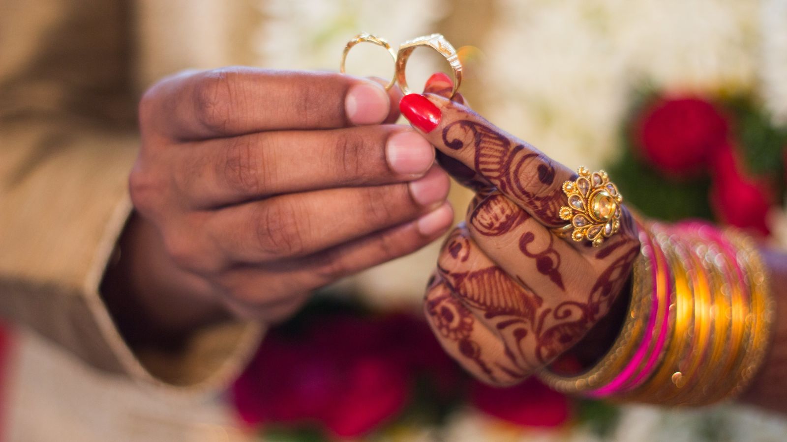 A close-up of a people's hands exchanging wedding rings