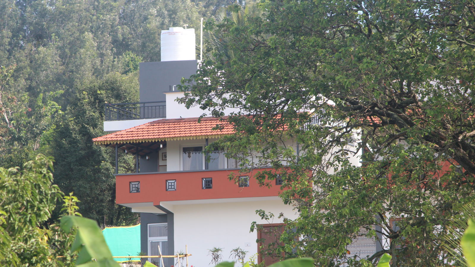 A view of a two-tiered house with an orange upper level amidst green trees