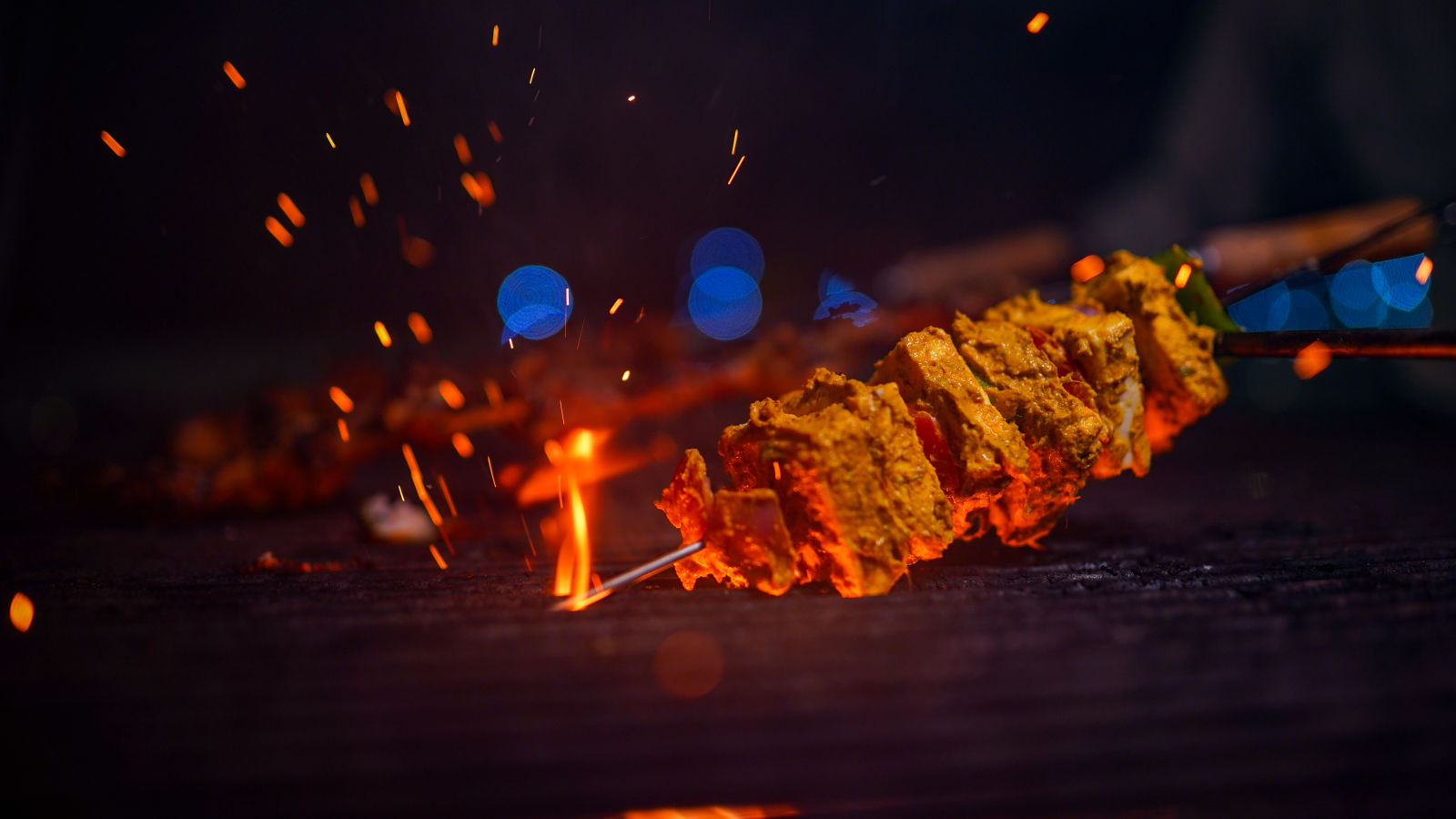 a person grilling paneer at night at La Montana By TGI, Ooty