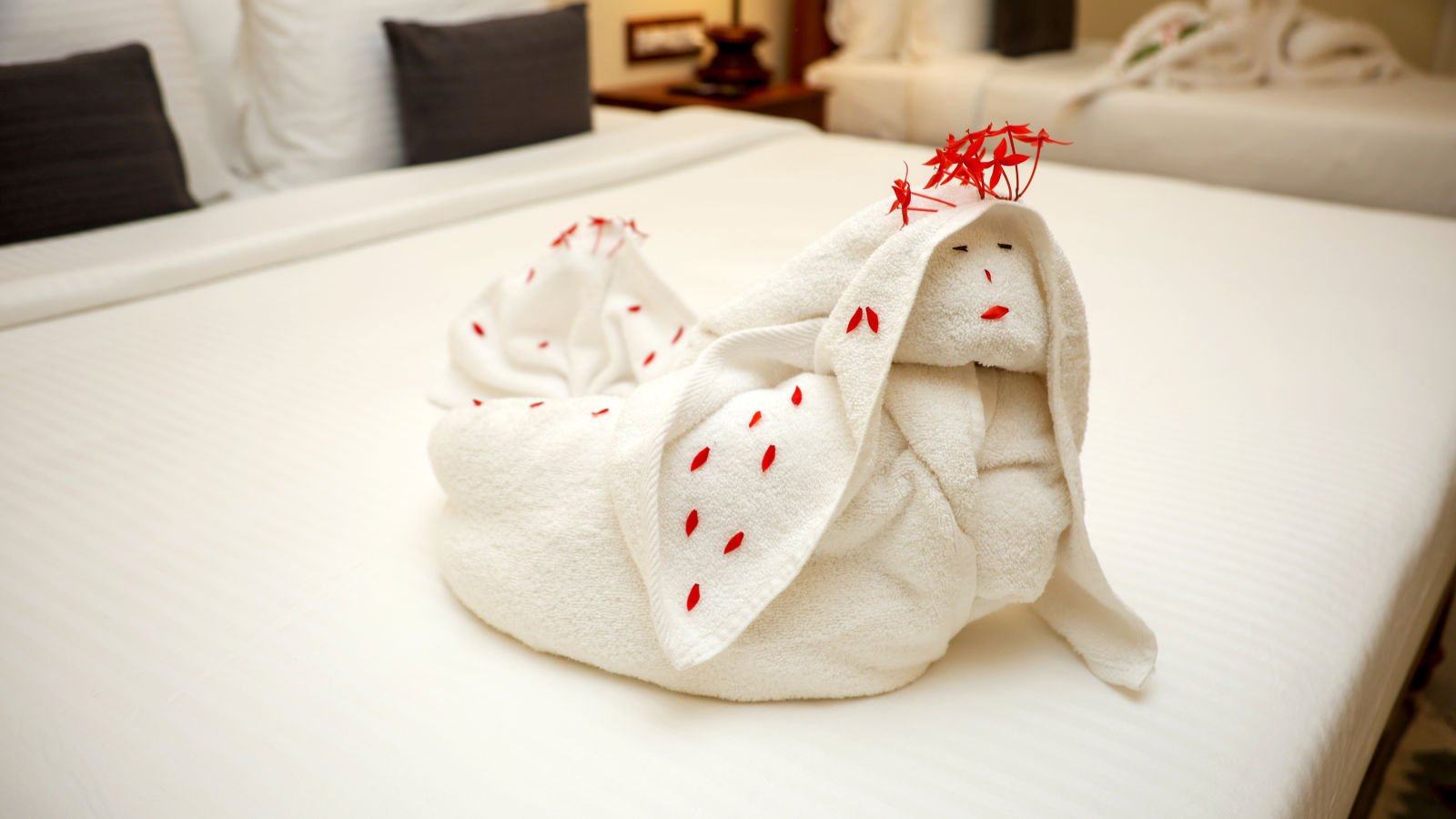 A bed decorate with towels and few flower petals  | Mango HIll La Serene, Ponicherry