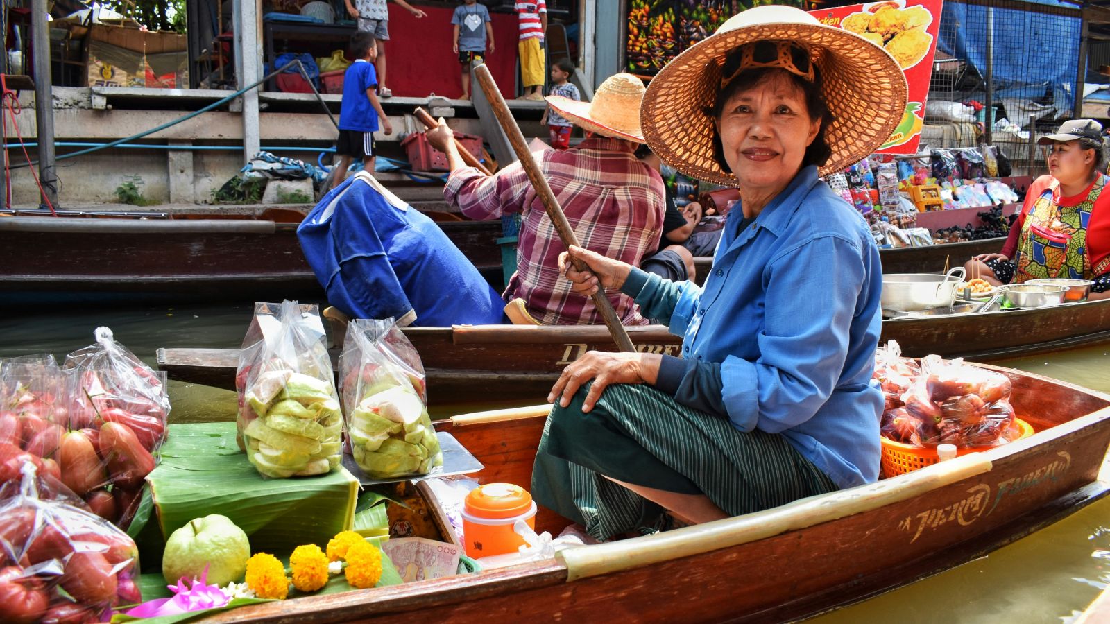 a person selling cut fruits in a floating market posing for a picture