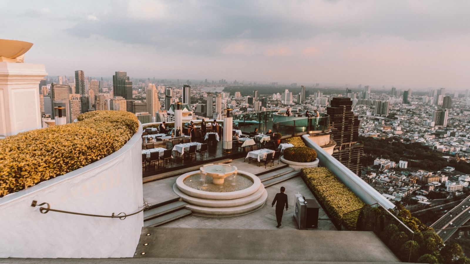 a rooftop bar in Bangkok with a city view and seating on the terrace