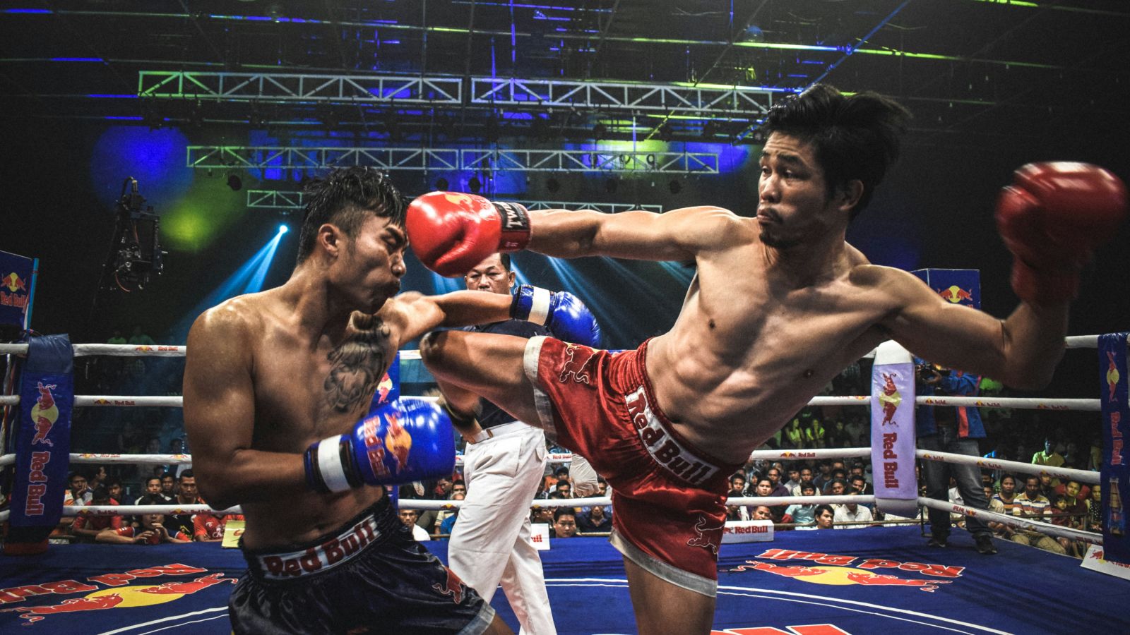 Two players competing in Muay Thai kick boxking in an arena