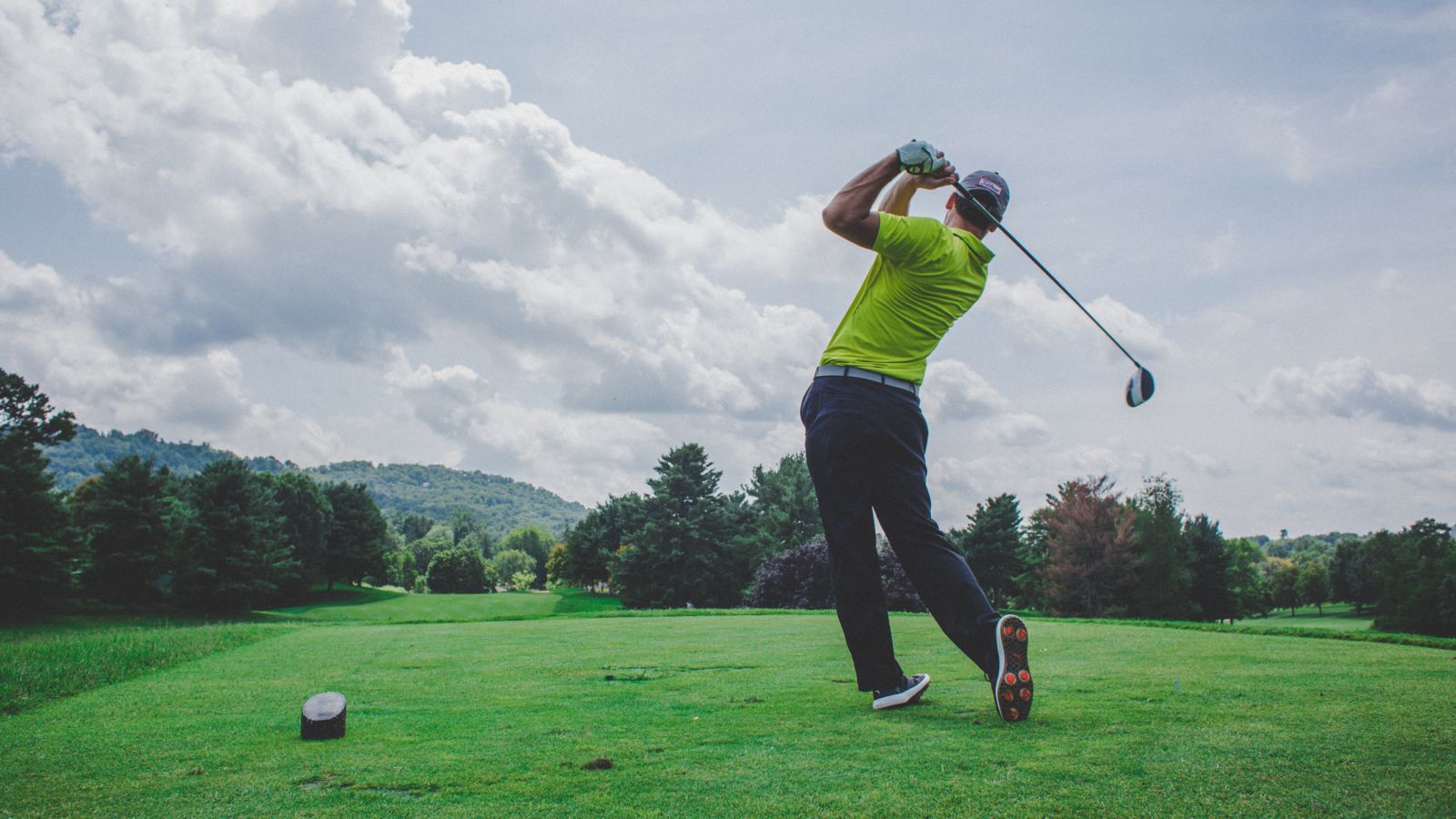 a person just finishing his golf swing after hitting the ball from the tee in a golf course