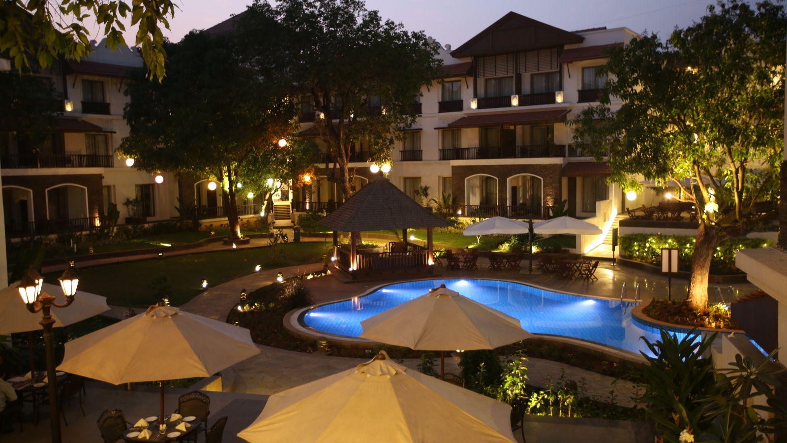 Courtyard with swimming pool lit up at night - Rhythm Lonavala