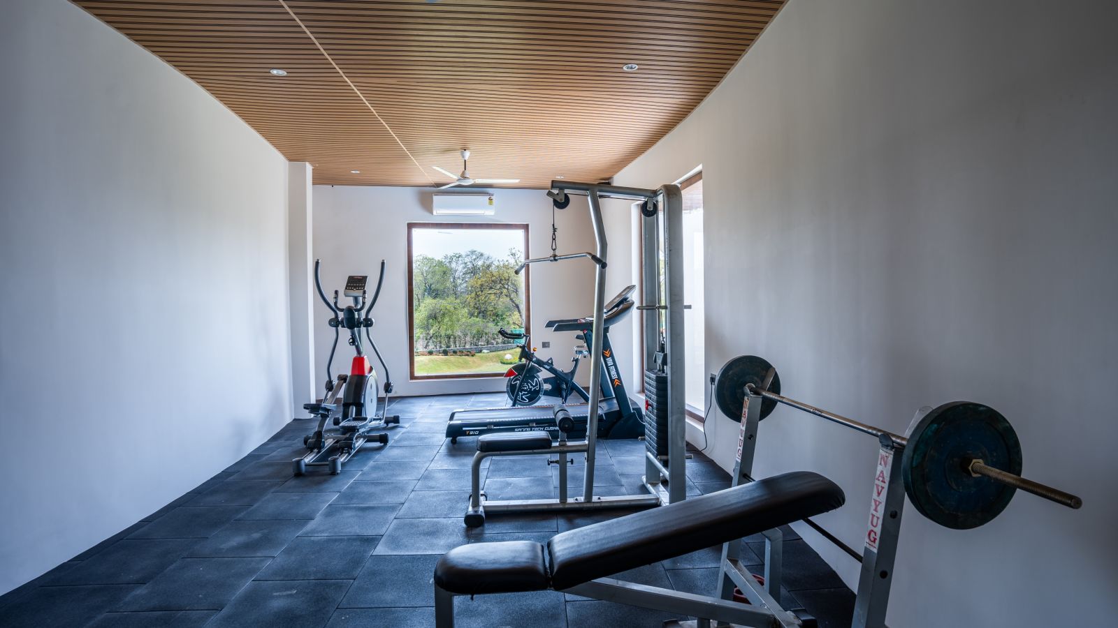 A gym room with cycling machines, a bench press, a thread mill and a lat pull down machine - Shervani Pebbles & Pines, Corbett