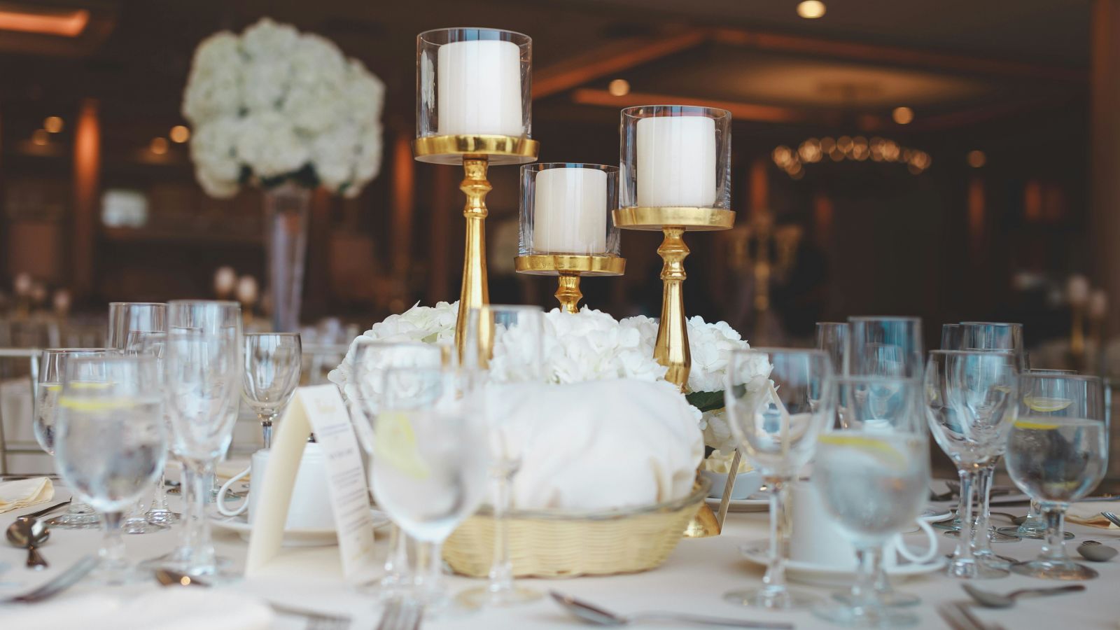 Sophisticated banquet table with gold candlesticks and white floral centrepieces