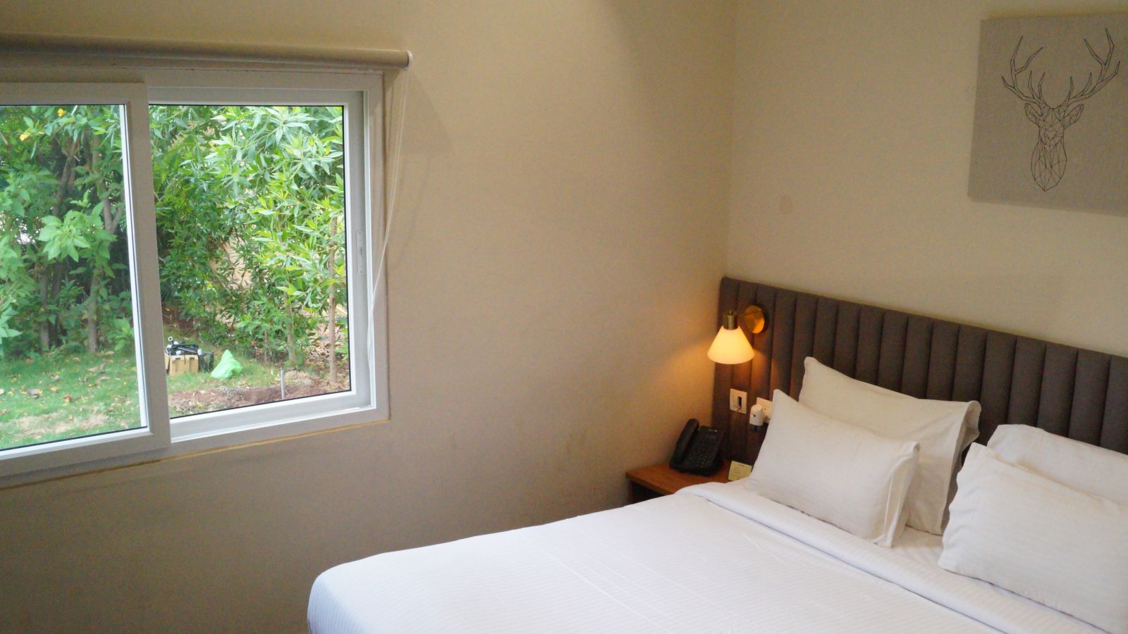 An image of the Hansa bedroom with a king size bed, and a window over seeing the lawn - Trance Veechika Resort