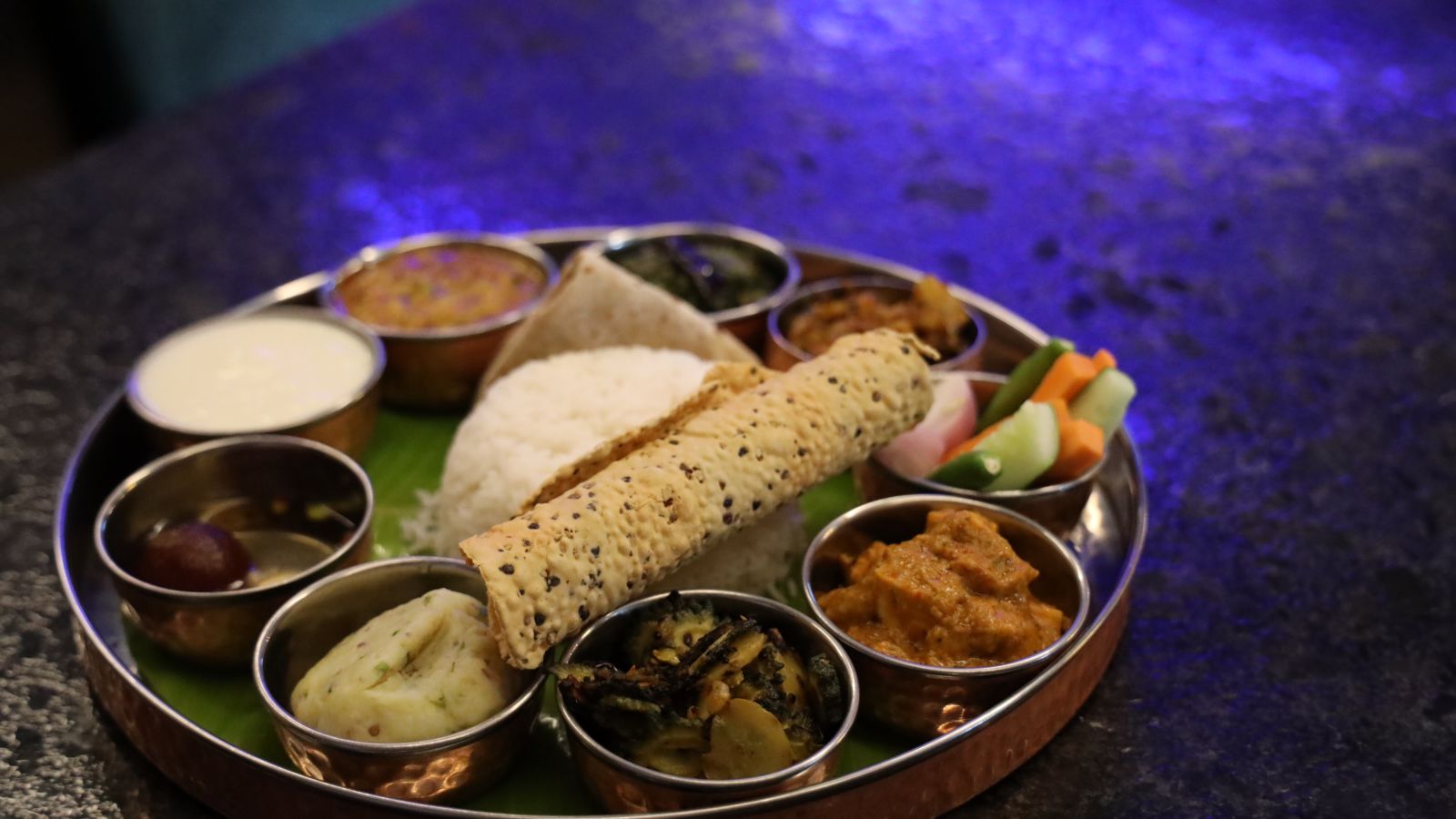 a plated thali with rice, papad and assorted vegetables - Wonderla Bhubaneswar