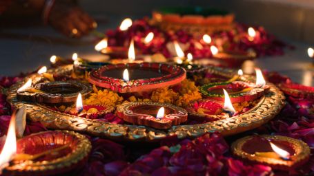 A close up shot of a copper plate with many lit diyas kept on it