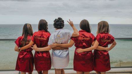 a bride and bridesmaids holding each other and looking into the sea with cloud cover - Bachelorette in Bangkok