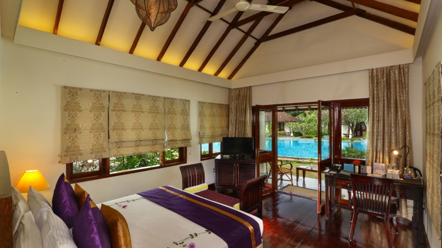 A room featuring a well made bed, a tv and a study desk - Rhythm Kumarakom