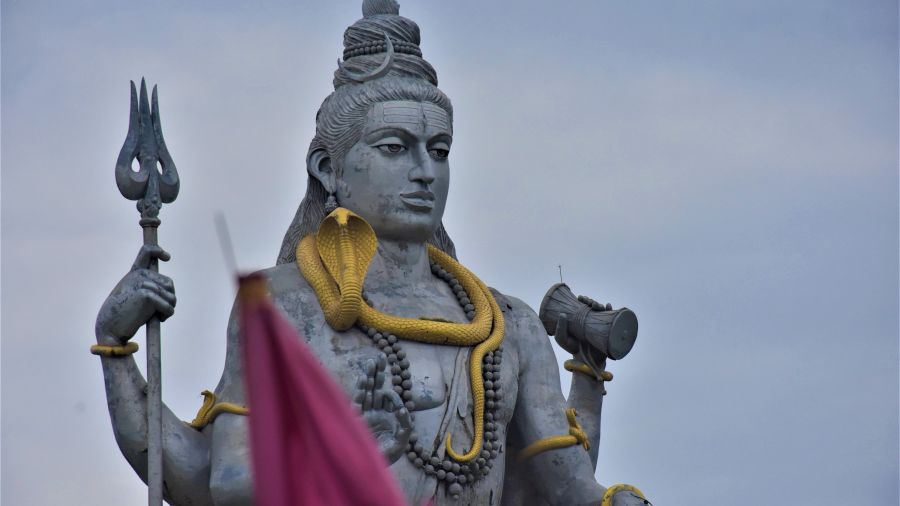 Close-up of a stone statue of Lord Shiva with a trident, draped in yellow fabric- Kumarakom 