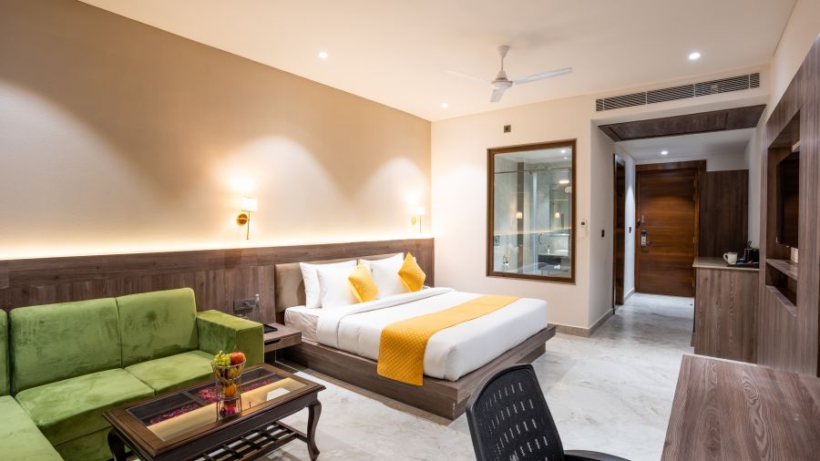 A premium room with a large bed, green sofas, a coffee table and a work desk - Shervani Pebbles & Pines, Corbett