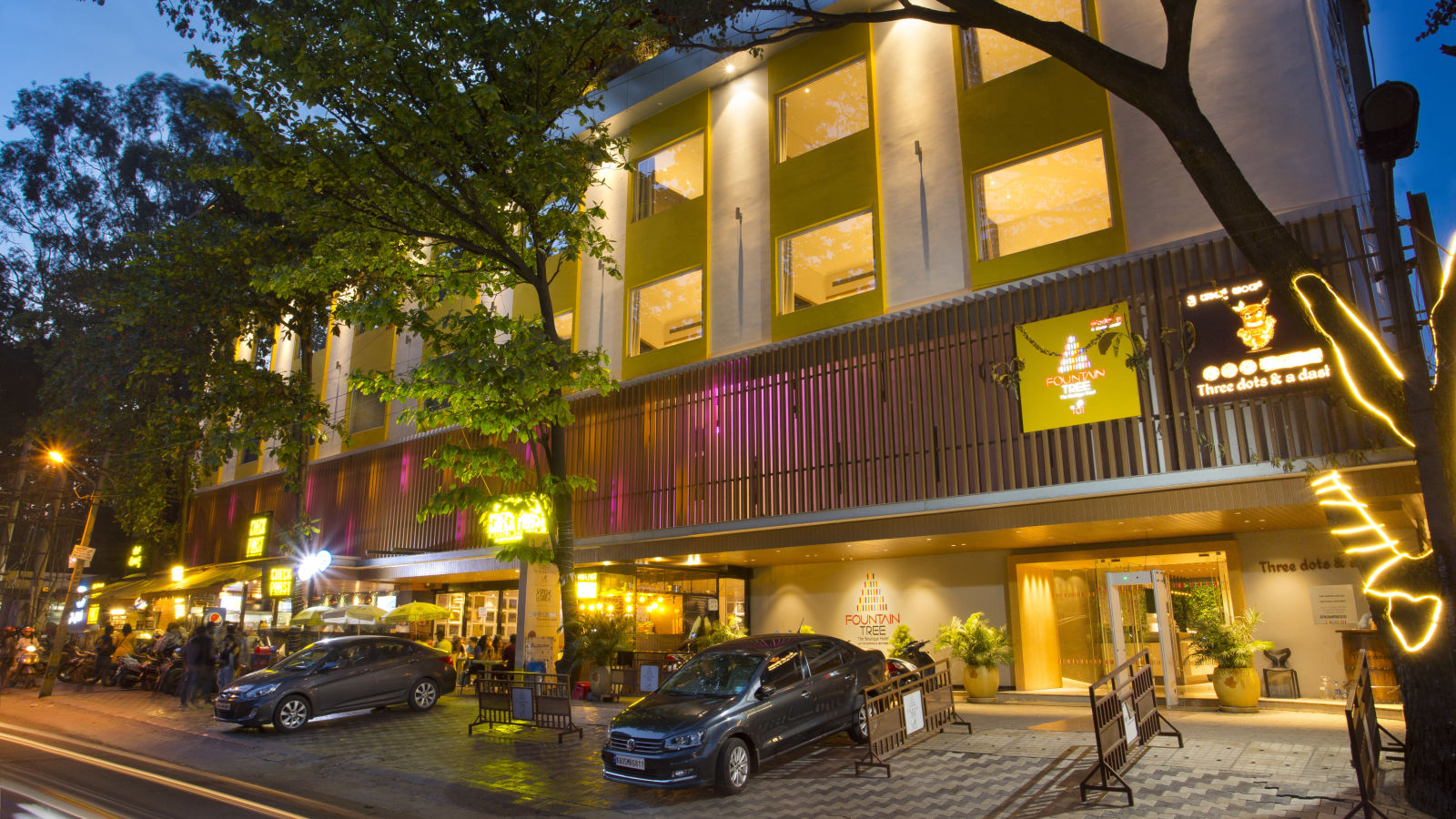 wide view of the facade of the hotel with cars parked outside the front - Hotel Fountain Tree By TGI - JP Nagar, Bangalore